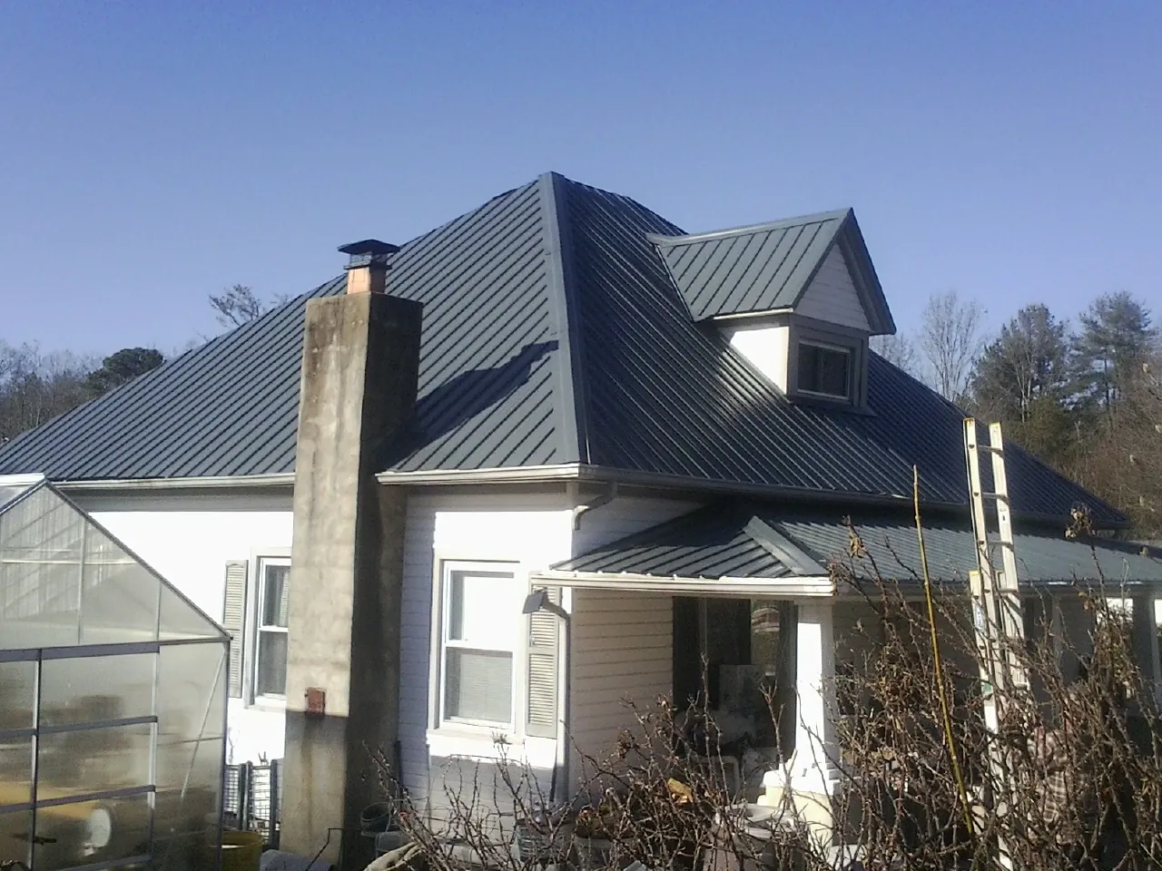 Dark blue standing seam metal roof on a white farmhouse with dormer — Slate & Tile Roof Repair by Roofing Brothers in Mattoon