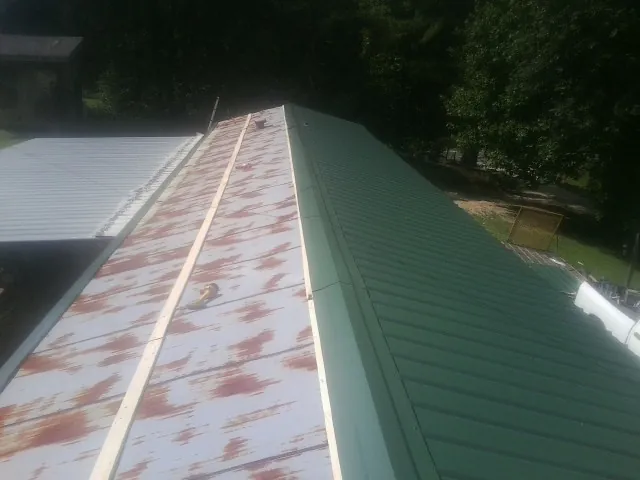 Old rusted panels beside newly installed green metal roofing — Wind Damage Roof Repair by Roofing Brothers in Mattoon