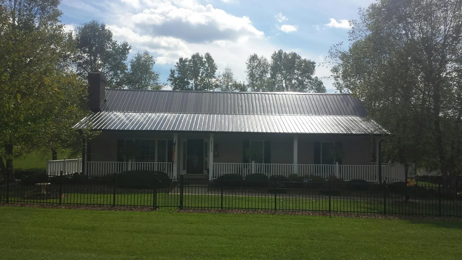 Gray metal roof on a brick ranch with a full width front porch — Gutter Guard Installation work by our crew in Mattoon