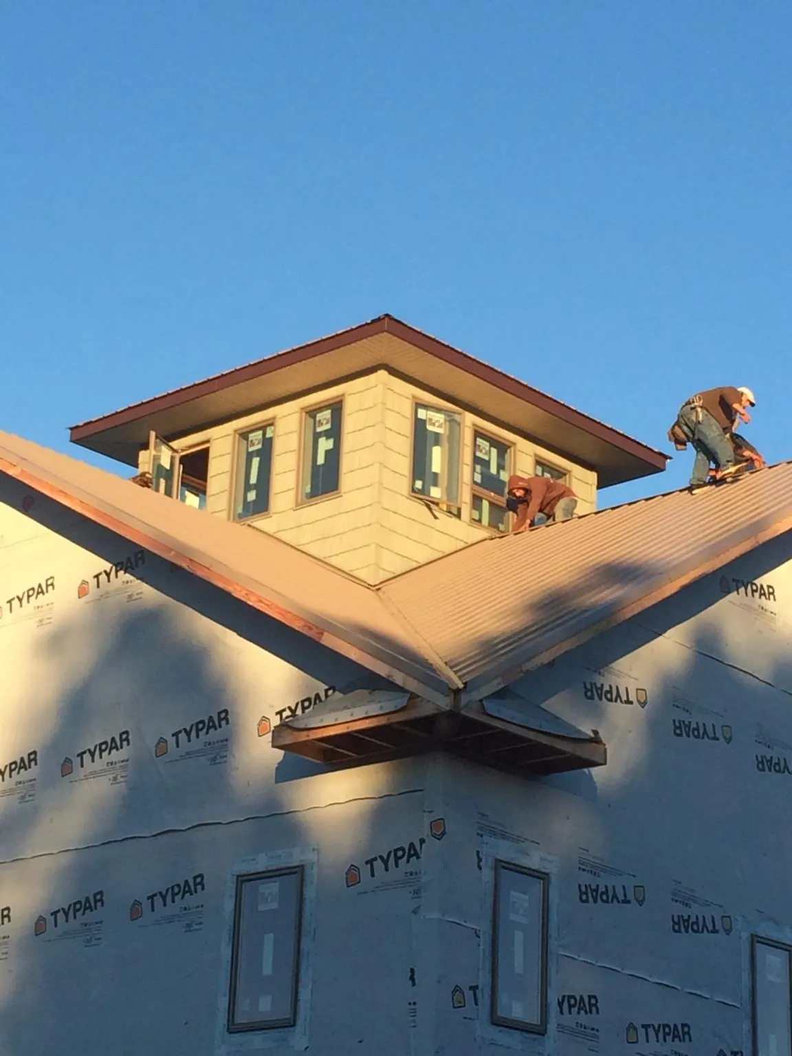 Roofers working around a rooftop cupola on a new metal roof at sunset — Roof Waterproofing in Mattoon by Roofing Brothers